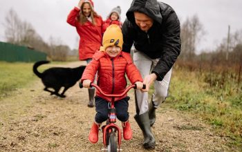 A joyful scene of a father helping his child ride a bike outdoors.