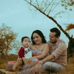 A family of three enjoying bonding time outdoors in a serene natural setting.
