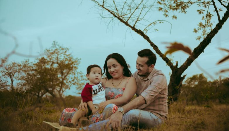 A family of three enjoying bonding time outdoors in a serene natural setting.
